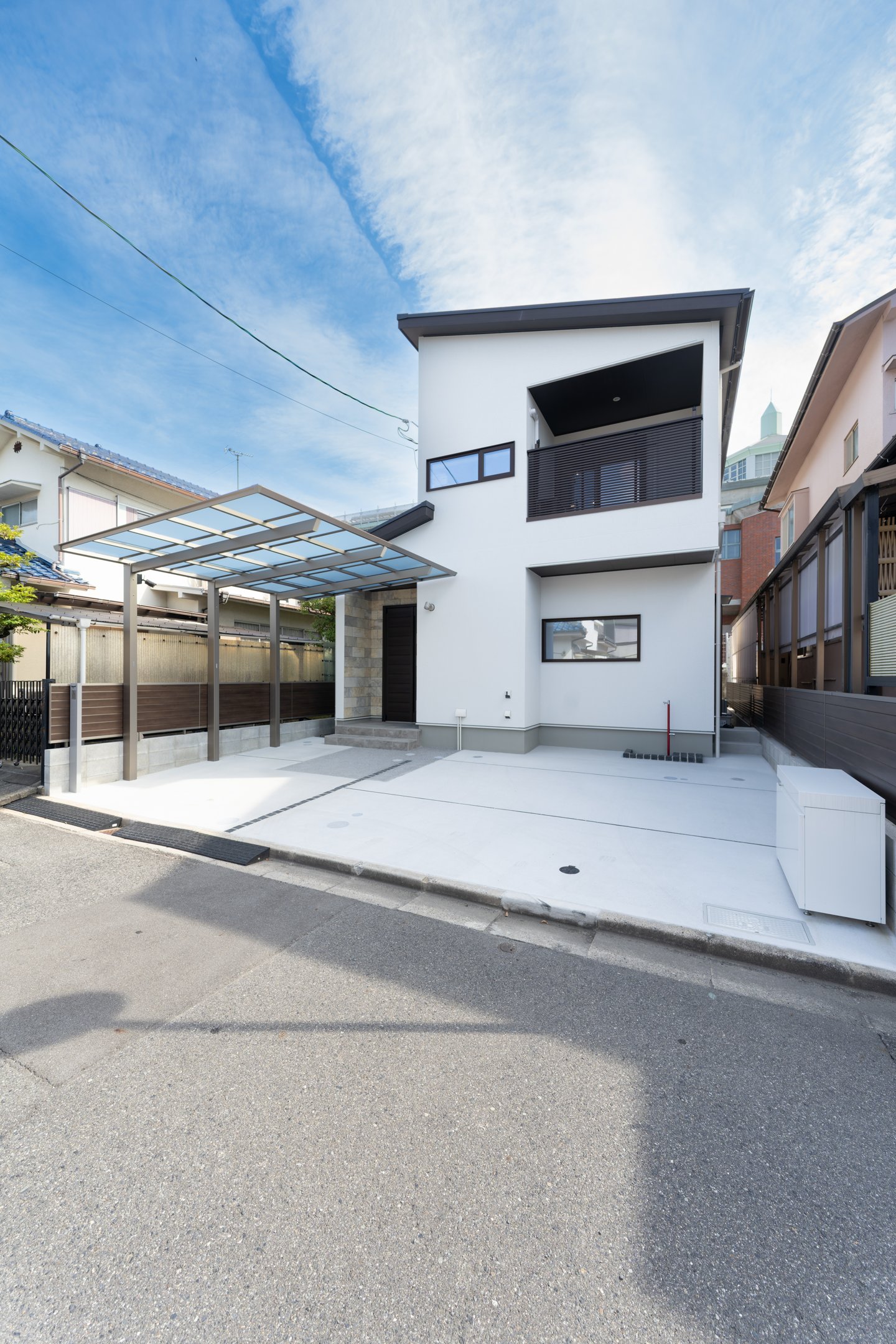 広島市佐伯区 素の家『遊学舎』の外観（白い塗り壁とカーポートのある駐車スペース）